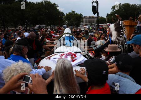 La gente posiziona le mani su un palo totem in preghiera durante una benedizione della scultura intagliata a mano che è stata trasportata attraverso il paese dallo stato di Washington a Washington, D.C. il palo totem era parte di un raduno sul centro commerciale nazionale il 29 luglio, 2021 per attirare l'attenzione e l'azione sui siti sacri e sui diritti indigeni (Foto di Bryan Olin Dozier/NurPhoto) Foto Stock