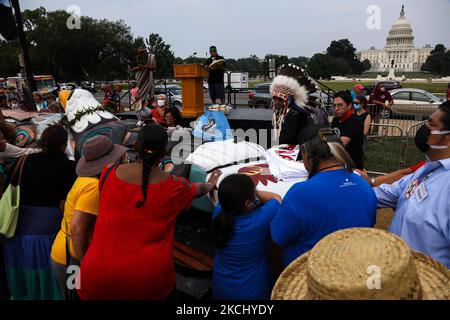 La gente posiziona le mani su un palo totem in preghiera durante una benedizione della scultura intagliata a mano che è stata trasportata attraverso il paese dallo stato di Washington a Washington, D.C. il palo totem era parte di un raduno sul centro commerciale nazionale il 29 luglio, 2021 per attirare l'attenzione e l'azione sui siti sacri e sui diritti indigeni (Foto di Bryan Olin Dozier/NurPhoto) Foto Stock