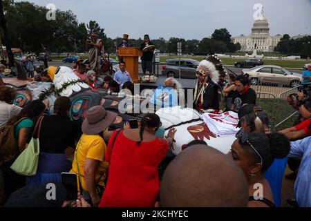 La gente posiziona le mani su un palo totem in preghiera durante una benedizione della scultura intagliata a mano che è stata trasportata attraverso il paese dallo stato di Washington a Washington, D.C. il palo totem era parte di un raduno sul centro commerciale nazionale il 29 luglio, 2021 per attirare l'attenzione e l'azione sui siti sacri e sui diritti indigeni (Foto di Bryan Olin Dozier/NurPhoto) Foto Stock