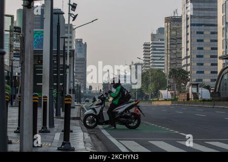 Un tassista del motociclo attende accanto alla strada principale durante la restrizione di attività pubblica di emergenza (PPKM) a Giacarta il 30 luglio 2021. Il presidente Joko “Jokowi” Widodo venerdì ha dichiarato che la restrizione di attività pubblica di emergenza (PKM) imposta dal governo il 3-20 luglio e si estende fino all'agosto 2, è stata efficace nel ridurre i casi COVID-19. Ha affermato che il governo non avrebbe mai preso in considerazione l’eventualità di un blocco. L'Indonesia sta attualmente adottando una restrizione PPPKM basata su livelli, con regolamenti più allentati per diversi settori delle microimprese. (Foto di Afriadi Hikmal/NurPhoto) Foto Stock