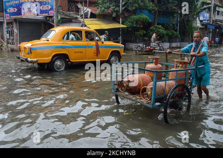 Un lavoratore trasporta una bombola di gas GPL in una strada allagata a Kolkata , India , il 30 luglio 2021 . i prezzi delle bombole di gas GPL sono stati innalzati di oltre 140 rupie negli ultimi 6 mesi , a causa dell' aumento dei prezzi del petrolio greggio . (Foto di Debarchan Chatterjee/NurPhoto) Foto Stock