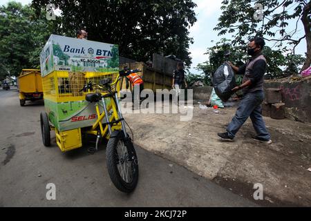 Un uomo trasporta un sacchetto di immondizia non-organico in un carico elettrico ecologico della bicicletta in un luogo di scarico vicino all'insediamento in Bogor, Java occidentale, Indonesia, il 4 agosto 2021. (Foto di Adriana Adie/NurPhoto) Foto Stock