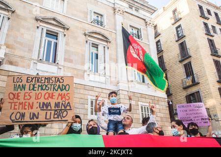 Un bambino è visto con una bandiera afghana accanto a manifestanti dietro una bandiera afghana e un segno che dice, gli estremisti hanno mostrato ciò che più temono: Una ragazza con un libro. Circa cinquecento persone hanno manifestato a Barcellona in solidarietà con le ragazze e le donne dell'Afghanistan e in difesa dei loro diritti sotto lo slogan "Afghanistan: Per una vita dignitosa e libera" (Photo by DAX Images/NurPhoto) Foto Stock