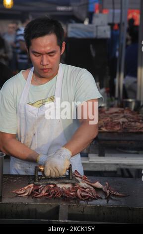 I barbecue dell'uomo squid su un bastone durante un mercato cinese di tutta la notte a Markham, Ontario, Canada, il 24 luglio 2015. (Foto di Creative Touch Imaging Ltd./NurPhoto) Foto Stock