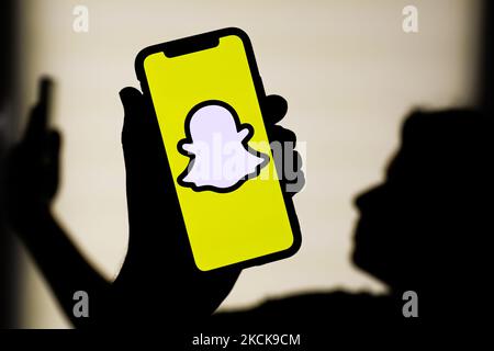 Il logo Snapchat visualizzato sullo schermo di un telefono e la silhouette di una donna con un telefono sullo sfondo sono visti in questa foto di illustrazione scattata a Cracovia, Polonia il 27 agosto 2021. (Foto Illustrazione di Jakub Porzycki/NurPhoto) Foto Stock