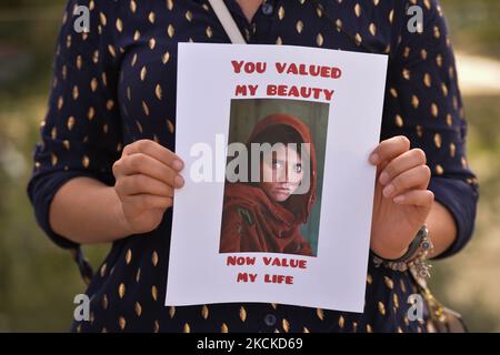 Un protester tiene la foto famosa ragazza afghana - un ritratto fotografico 1984 di Sharbat Gulla del fotogiornalista Steve McCurry con le parole 'avete valutato la mia bellezza, ora voi stimate la mia vita.' Membri della diaspora afghana locale, attivisti e sostenitori locali visti di fronte al Palazzo della Legislatura di Alberta durante LA FERMATA UCCIDENDO AFGHANI! Protesta organizzata oggi dal movimento globale per la pace in Afghanistan. Sabato 28 agosto 2021, a Edmonton, Alberta, Canada. (Foto di Artur Widak/NurPhoto) Foto Stock