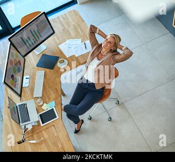 Dopo una giornata produttiva, una donna d'affari matura che si prende una pausa alla scrivania. Foto Stock