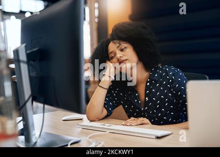 Mi riposerò gli occhi per un secondo. Una giovane designer stanca che si addormenta dietro il computer in ufficio durante il giorno. Foto Stock