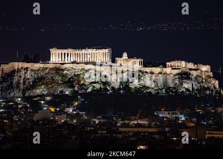 Vista notturna del Partenone e dell'Acropoli con un traghetto che passa sullo sfondo della capitale greca Athina. La tecnica fotografica a lunga esposizione mostra le antichità illuminate al buio con il paesaggio urbano della città intorno. L'antica collina dell'Acropoli, tra cui il tempio in marmo del Partenone, conosciuto in tutto il mondo, e i resti di molti edifici antichi di grande importanza architettonica e storica come l'Erechtheion, Propylaia, il tempio di Atena Nike, i cariadi e molto altro ancora. Durante l'occupazione ottomana, l'Acropoli fu reciso da gravi danni. Oggi è patrimonio mondiale dell'UNESCO Foto Stock