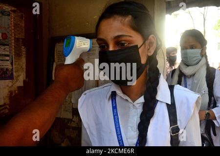 Un funzionario controlla la temperatura corporea di uno studente al suo arrivo alla Azimpur Government Girls School and College di Dhaka, Bangladesh, il 12 settembre 2021. Dopo 543 giorni, le scuole primarie, secondarie e superiori di tutto il paese hanno riaperto mantenendo le linee guida e i protocolli sanitari del Covid-19. (Foto di Mamunur Rashid/NurPhoto) Foto Stock