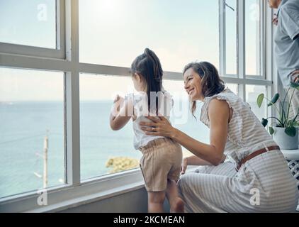 Vista della famiglia, finestra e madre con bambino legame, divertirsi e godersi il tempo di qualità insieme nel salotto di casa. Mamas amore, felicità e mamma con Foto Stock