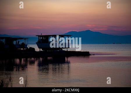 Una barca da pesca fuori nella terra. L'alba, l'alba e il sole che si riflettono sul mare al Parco Nazionale del Delta di Axios, un luogo con zone umide vicino Halastra e la città di Salonicco, dove 4 fiumi Gallikos, Axios, Loudias e Aliakomnas hanno il loro delta. Nella località specifica pescatori e produttori di mitili hanno le loro capanne e barche. A proposito della biodiversità, questa regione è famosa e di importanza ornitologica mondiale, poiché qui si fermano, nidificano o sopraviventi popolazioni considerevoli di uccelli rari, mentre sono documentate 299 specie di uccelli. Quanto a Flore e Fauna più di 370 specie di piante hanno Foto Stock