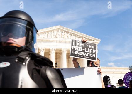 Un controprestante pro-vita ha un segno dietro un ufficiale della polizia del Campidoglio in attrezzatura antisommossa mentre la marcia delle donne per la giustizia dell'aborto passa davanti alla Corte Suprema degli Stati Uniti. I manifestanti chiedono al governo degli Stati Uniti di proteggere i diritti riproduttivi delle donne e l'accesso all'aborto in tutto il paese. In particolare, chiedono al Congresso di approvare la Legge sulla protezione della salute delle donne (WHPA) e CIASCUNA Legge, che garantiscono l'accesso all'aborto e richiedono che sia coperta da un'assicurazione. Più di 600 proteste satellitari si stanno verificando a livello nazionale il 2 ottobre. Gli eventi sono in parte in risposta alle leggi anti-aborto restrittive recentemente approvate Foto Stock