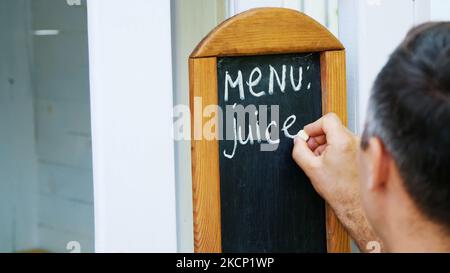 primo piano, su lavagna uomo scrivere con gesso bianco, parole-menu, succo. Foto di alta qualità Foto Stock