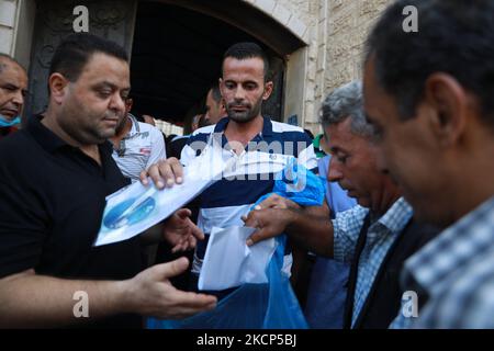 Gli uomini palestinesi si riuniscono per richiedere permessi di lavoro in Israele, nel campo profughi di Jabalia nella striscia di Gaza settentrionale, il 6 ottobre 2021. (Foto di Majdi Fathi/NurPhoto) Foto Stock