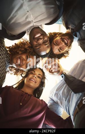 Le cose buone accadono quando mettiamo la testa insieme. Ritratto ad angolo basso di un team di uomini d'affari felici mettendo la testa insieme in una huddle. Foto Stock