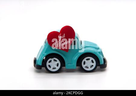 Mini macchina giocattolo con forma a cuore rosso e testo appena sposato. Concetto di recentemente mer. Foto Stock