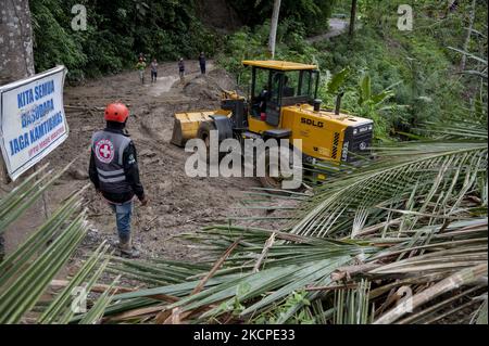 Gli operatori delle attrezzature pesanti rimuovono il materiale che ha bloccato la strada Trans Palu-Kulawi a causa di inondazioni e frane improvvise nel villaggio di Salua, distretto di Kulawi, reggenza di Sigi, provincia di Sulawesi centrale, Indonesia il 11 ottobre 2021. L'alluvione che si è verificata il 10 ottobre 2021 notte a causa di forti piogge ha causato decine di case gravemente danneggiate, e ben 42 capi di famiglie sono stati costretti a fuggire in luoghi sicuri, tra cui le chiese locali. In precedenza, l'agenzia locale di meteorologia, climatologia e geofisica (BMKG) aveva avvertito di un potenziale disastro con previsioni di pioggia e forti venti in Seve Foto Stock