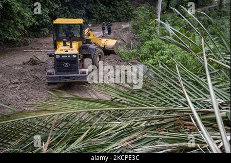 Gli operatori delle attrezzature pesanti rimuovono il materiale che ha bloccato la strada Trans Palu-Kulawi a causa di inondazioni e frane improvvise nel villaggio di Salua, distretto di Kulawi, reggenza di Sigi, provincia di Sulawesi centrale, Indonesia il 11 ottobre 2021. L'alluvione che si è verificata il 10 ottobre 2021 notte a causa di forti piogge ha causato decine di case gravemente danneggiate, e ben 42 capi di famiglie sono stati costretti a fuggire in luoghi sicuri, tra cui le chiese locali. In precedenza, l'agenzia locale di meteorologia, climatologia e geofisica (BMKG) aveva avvertito di un potenziale disastro con previsioni di pioggia e forti venti in Seve Foto Stock