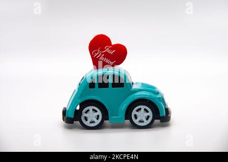 Mini macchina giocattolo con forma a cuore rosso e testo appena sposato. Concetto di recentemente mer. Foto Stock