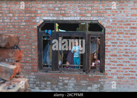 La gente di Kashmiri guarda fuori da una casa residenziale danneggiata dove una battaglia delle armi ha avuto luogo tra le forze indiane e i militanti di Kashmiri nel villaggio di Tulran del distretto di Pulwama a sud di Srinagar, indiano amministrato Kashmir il 12 ottobre 2021. Sette militanti Kashmiri e cinque soldati paramilitari indiani sono stati uccisi in molteplici incontri attraverso la Valle. Anche tre case residenziali sono state danneggiate durante la battaglia di armi. (Foto di Muzamil Mattoo/NurPhoto) Foto Stock