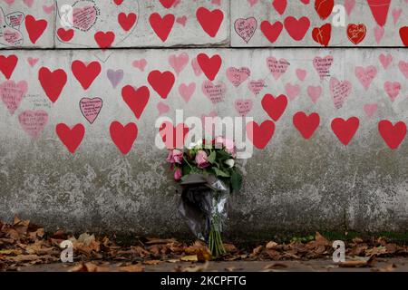 I fiori riposano ai piedi del National Covid Memorial Wall, sulla sponda sud del Tamigi, di fronte alle Houses of Parliament di Londra, Inghilterra, il 12 ottobre 2021. Il muro, creato questa primavera, è costituito da più di 150.000 cuori dipinti, ciascuno che rappresenta una vita persa nel paese per covid-19. Oggi nel frattempo è stata pubblicata la relazione "Coronavirus: Lezioni apprese fino ad oggi" dei parlamentari sui comitati per la salute e l'assistenza sociale e la scienza e la tecnologia, che critica fortemente l'approccio del governo alla gestione delle prime fasi della pandemia di coronavirus, ma Foto Stock