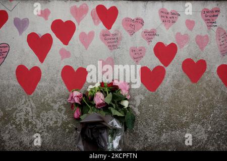 I fiori riposano ai piedi del National Covid Memorial Wall, sulla sponda sud del Tamigi, di fronte alle Houses of Parliament di Londra, Inghilterra, il 12 ottobre 2021. Il muro, creato questa primavera, è costituito da più di 150.000 cuori dipinti, ciascuno che rappresenta una vita persa nel paese per covid-19. Oggi nel frattempo è stata pubblicata la relazione "Coronavirus: Lezioni apprese fino ad oggi" dei parlamentari sui comitati per la salute e l'assistenza sociale e la scienza e la tecnologia, che critica fortemente l'approccio del governo alla gestione delle prime fasi della pandemia di coronavirus, ma Foto Stock