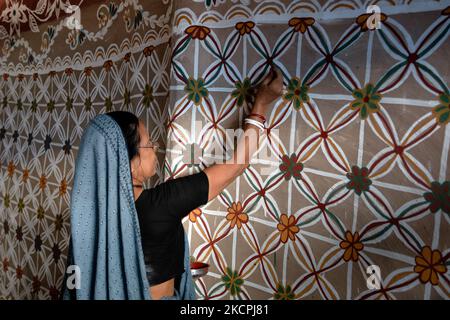 Una donna disegna motivi tradizionali su un muro della sua casa al villaggio di Tikoil a Nachole upazila del distretto di Chapainawabbanj del Bangladesh. (Foto di Mushfiqul Alam/NurPhoto) Foto Stock