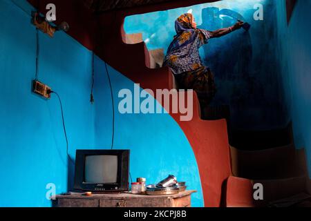 Una donna disegna motivi tradizionali su un muro della sua casa al villaggio di Tikoil a Nachole upazila del distretto di Chapainawabbanj del Bangladesh. (Foto di Mushfiqul Alam/NurPhoto) Foto Stock