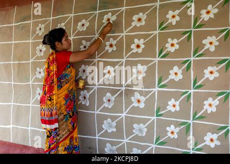 Una donna disegna motivi tradizionali su un muro della sua casa al villaggio di Tikoil a Nachole upazila del distretto di Chapainawabbanj del Bangladesh. (Foto di Mushfiqul Alam/NurPhoto) Foto Stock