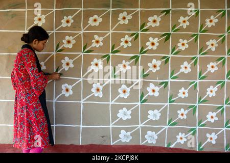 Una donna disegna motivi tradizionali su un muro della sua casa al villaggio di Tikoil a Nachole upazila del distretto di Chapainawabbanj del Bangladesh. (Foto di Mushfiqul Alam/NurPhoto) Foto Stock