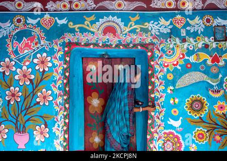 Una donna disegna motivi tradizionali su un muro della sua casa al villaggio di Tikoil a Nachole upazila del distretto di Chapainawabbanj del Bangladesh. (Foto di Mushfiqul Alam/NurPhoto) Foto Stock