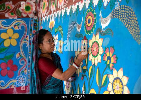 Una donna disegna motivi tradizionali su un muro della sua casa al villaggio di Tikoil a Nachole upazila del distretto di Chapainawabbanj del Bangladesh. (Foto di Mushfiqul Alam/NurPhoto) Foto Stock