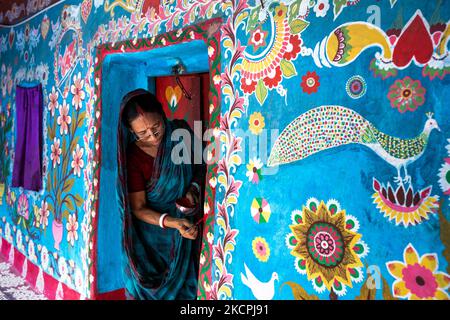 Una donna disegna motivi tradizionali su un muro della sua casa al villaggio di Tikoil a Nachole upazila del distretto di Chapainawabbanj del Bangladesh. (Foto di Mushfiqul Alam/NurPhoto) Foto Stock