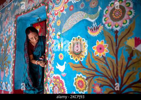 Una donna disegna motivi tradizionali su un muro della sua casa al villaggio di Tikoil a Nachole upazila del distretto di Chapainawabbanj del Bangladesh. (Foto di Mushfiqul Alam/NurPhoto) Foto Stock