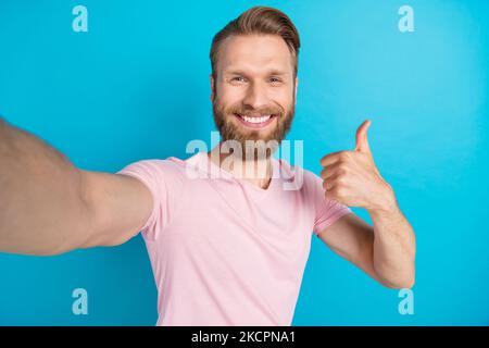 Ritratto fotografico di bel giovane uomo pollice su selfie video chiamata registrazione vestito elegante look rosa isolato su sfondo color acquamarina Foto Stock