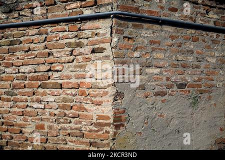 Angolo di un muro di mattoni con tubazioni su di esso Foto Stock