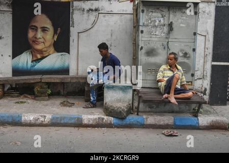 Si vedono persone che riposano accanto a una foto del Capo Ministro del Bengala Occidentale Mamata Banerjee , in una strada a Kolkata , in India , il 25 ottobre 2021 . (Foto di Debarchan Chatterjee/NurPhoto) Foto Stock