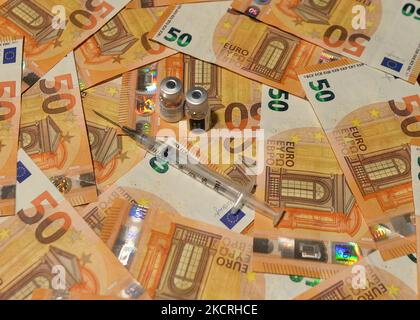 Un'immagine illustrativa di cinquanta banconote in euro, una siringa medica e fiale di vaccino. Lunedì 25 ottobre 2021, a Edmonton, Alberta, Canada. (Foto di Artur Widak/NurPhoto) Foto Stock