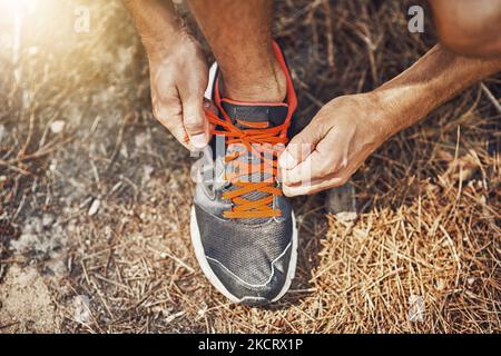 Leghi i vostri lacci saldamente per evitare di inciampare. Un giovane legando i loro lacci prima di andare per una corsa all'aperto. Foto Stock