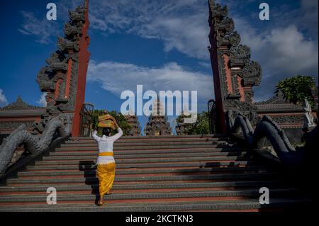 Un adoratore indù entra nel tempio per assistere alla preghiera della Giornata Galungana a pura Agung Wanakerta Jagatnatha a Palu, nella Provincia Centrale di Sulawesi, Indonesia il 10 novembre 2021. Le preghiere Galungan nella zona sono tenute a rotazione in due gruppi, il mattino e la sera gruppi per evitare la folla di persone per prevenire la diffusione di COVID-19. Il governo locale autorizza i residenti a svolgere attività di culto, ma è limitato al 50% della capacità del luogo di culto. (Foto di Basri Marzuki/NurPhoto) Foto Stock