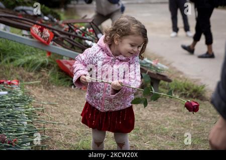 Una bambina tiene un garofano vicino a un monumento all'interno del Politecnico di Atene, per celebrare il 48th° anniversario di una rivolta studentesca del 1973 contro la giunta militare che governava il paese all'epoca ad Atene, in Grecia, il 16 novembre 2021. (Foto di Nikolas Kokovlis/NurPhoto) Foto Stock