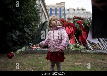 Una bambina tiene un garofano vicino a un monumento all'interno del Politecnico di Atene, per celebrare il 48th° anniversario di una rivolta studentesca del 1973 contro la giunta militare che governava il paese all'epoca ad Atene, in Grecia, il 16 novembre 2021. (Foto di Nikolas Kokovlis/NurPhoto) Foto Stock