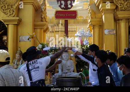 I devoti buddisti versano acqua su una statua di Buddha durante il giorno della luna piena di Tazaungmon, l'ottavo mese del calendario del Myanmar, alla Pagoda di Shwedagon a Yangon, Myanmar il 18 novembre 2021. (Foto di Myat Thu Kyaw/NurPhoto) Foto Stock