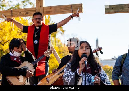 Padre Jose Landaverde, attivista dell'immigrazione, è appeso su una croce di legno durante un'azione diretta della National TPS Alliance alla Casa Bianca. Gli attivisti sono appesi sulle croci per 8 ore per simboleggiare il sacrificio che gli immigrati fanno per contribuire alla vita negli Stati Uniti con un lungo e duro lavoro. Una banda di giovani di una scuola di mariachi suona di fronte a Padre Landaverde. Fanno parte di un raduno che celebra il vertice del presidente messicano Andrés Manuel Lopez Obrador con il presidente Joe Biden e il ministro canadese Peime Justin Trudeau, nonché la richiesta di una riforma dell’immigrazione. (Foto di Allison Bailey/NurPhoto) Foto Stock