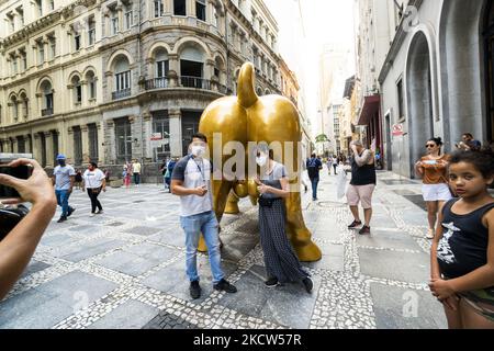 La gente posa accanto alla statua 'Charging Bull' (conosciuta come Bull Wall Street) replica di fronte alla Borsa di San Paolo (B3) sede, a San Paolo, Brasile, il 18 novembre 2021 (Foto di Cris FAGA/NurPhoto) Foto Stock