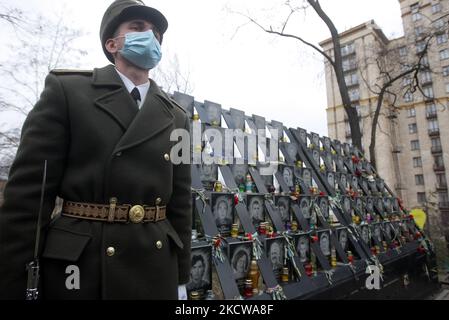 Un militare ucraino partecipa a una cerimonia di commemorazione in un monumento di Eroi di Heavenly Hundred, attivisti che sono stati uccisi durante la protesta anti-governativa della rivoluzione Euro Maidan nel 2014, a Kiev, in Ucraina, il 21 novembre 2021. Gli ucraini segnano l'anniversario della rivoluzione EuroMaidan o della rivoluzione della dignità. (Foto di Str/NurPhoto) Foto Stock