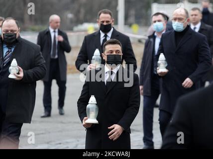 Il presidente ucraino Volodymyr Zelensky (C) mette una candela ad un monumento di Eroi di Heavenly Hundred, attivisti che sono stati uccisi durante la protesta anti-governativa della rivoluzione Euro Maidan nel 2014, durante una cerimonia di commemorazione a Kyiv, Ucraina il 21 novembre 2021. Gli ucraini segnano l'anniversario della rivoluzione EuroMaidan o della rivoluzione della dignità. (Foto di Str/NurPhoto) Foto Stock