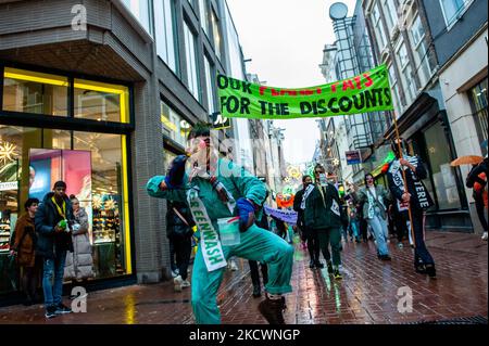 Un clown che rappresenta le pratiche di lavaggio del verde condotte dai marchi della moda, finge di dipingere con vernice verde, durante una sfilata di moda beffa Fast organizzata da XR, contro il Black Friday ad Amsterdam, il 27th novembre 2021. (Foto di Romy Arroyo Fernandez/NurPhoto) Foto Stock