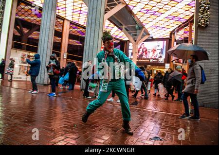 Un clown che rappresenta le pratiche di lavaggio del verde condotte dai marchi della moda, finge di dipingere con vernice verde, durante una sfilata di moda beffa Fast organizzata da XR, contro il Black Friday ad Amsterdam, il 27th novembre 2021. (Foto di Romy Arroyo Fernandez/NurPhoto) Foto Stock